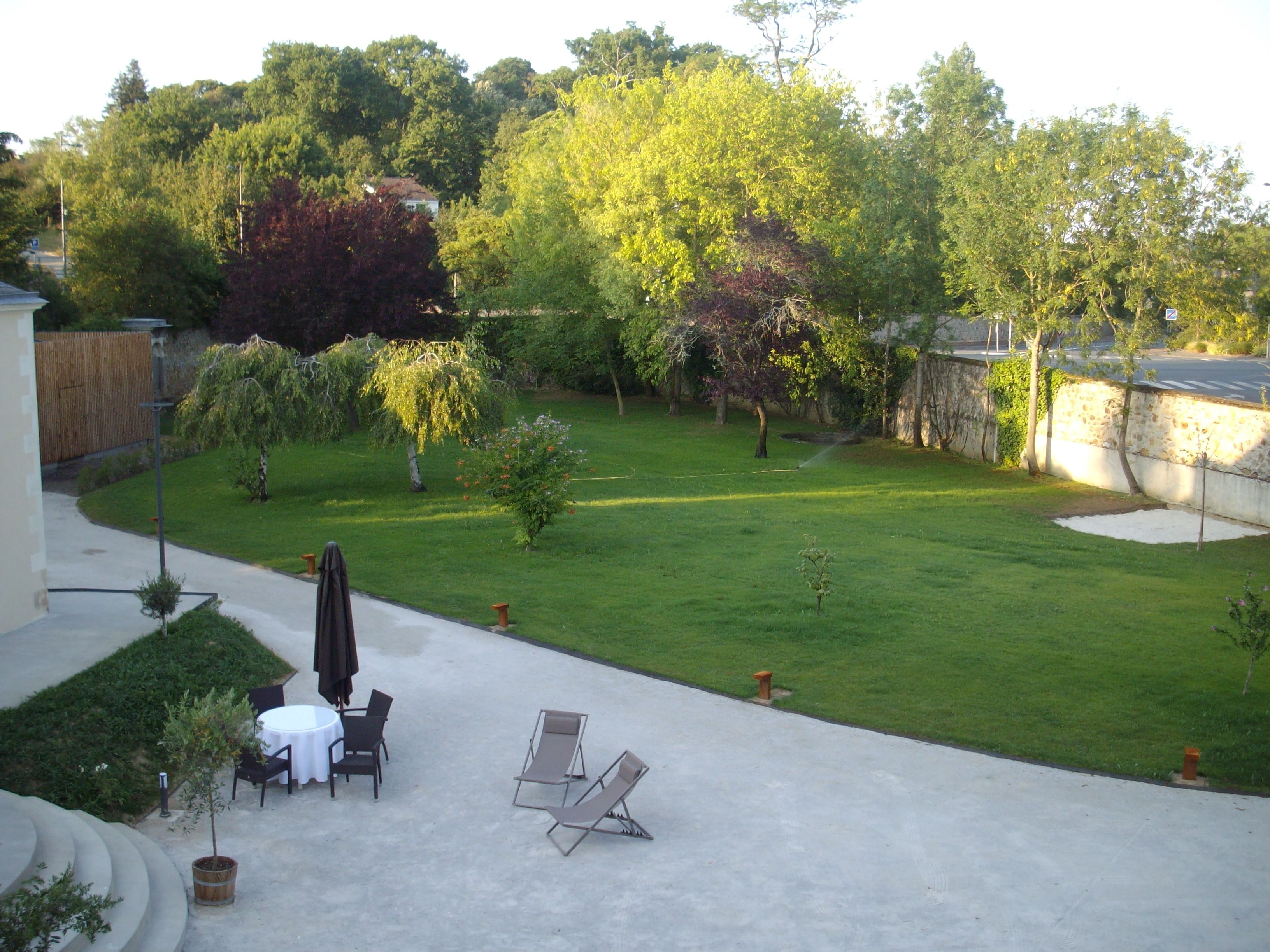 A backyard with a patio area, a lawn, and a stone wall.