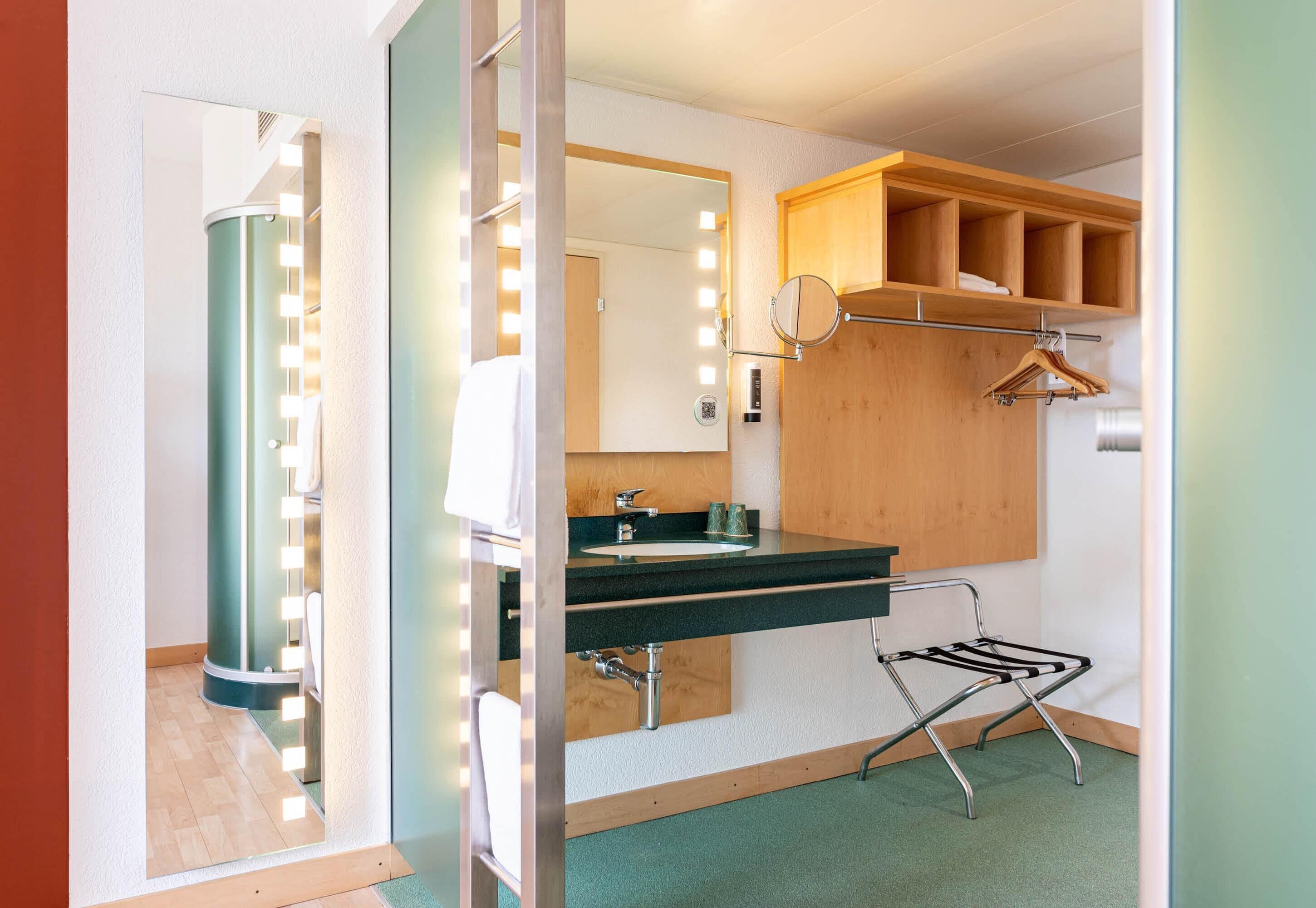 Une salle de bain équipée d’un meuble-lavabo, d’un miroir, de luminaires et d’un porte-serviettes.