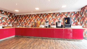 Eine moderne Küche mit roten Schränken, Holzboden und einer Wand mit Muster.