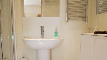 A bathroom with a white sink, a toilet, and a glass shower enclosure.