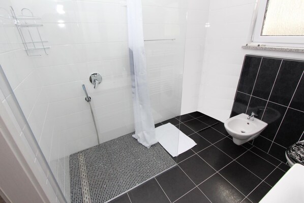 A bathroom with a shower, a bidet, and a tiled floor. - Apartment Karlo 1 (Rovinj)