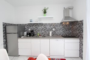 A modern kitchen with white cabinets, a stainless steel refrigerator, a built-in dishwasher, and a patterned backsplash. - Apartment Karlo 1 (Rovinj)