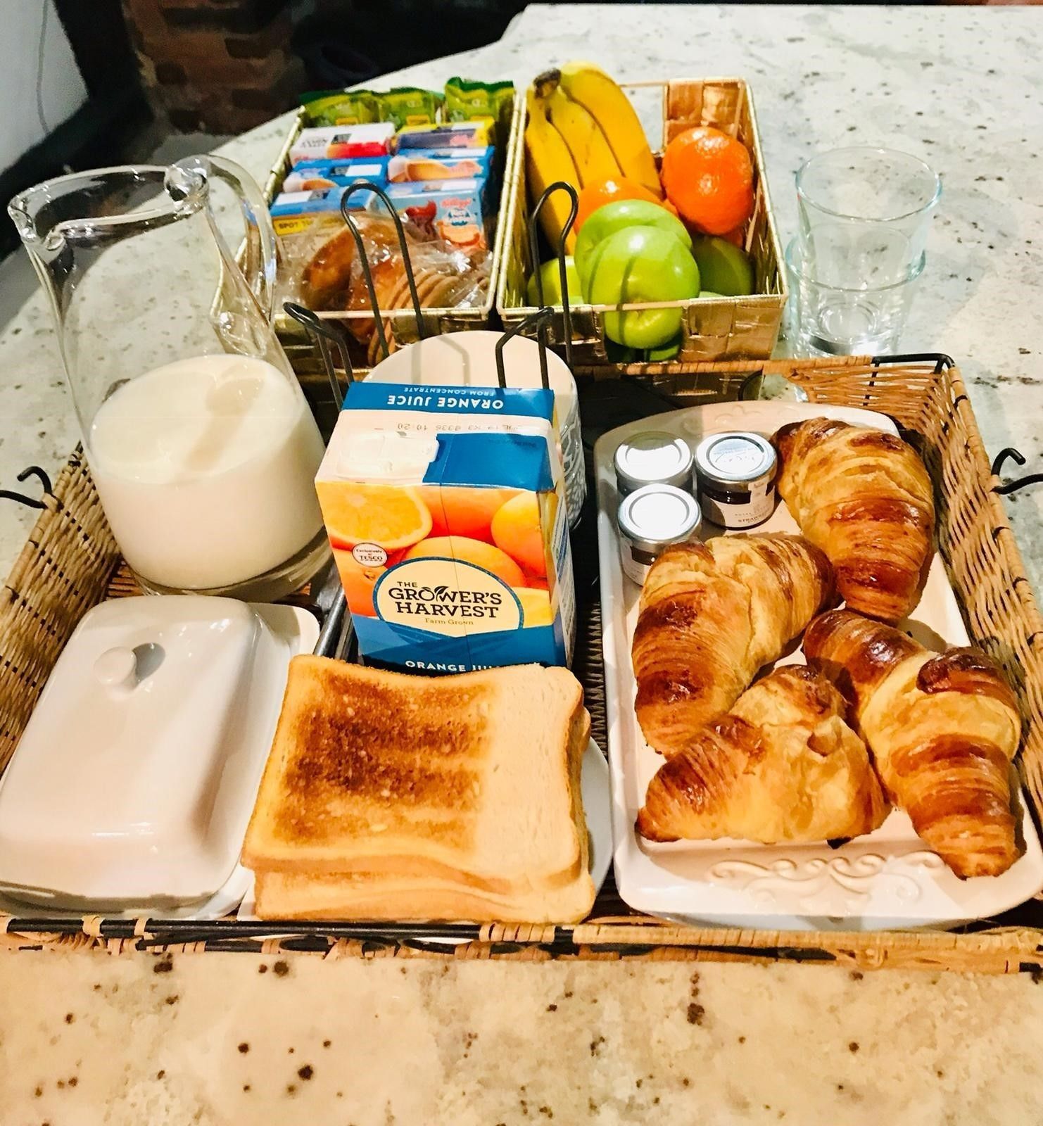 A breakfast spread with orange juice, toast, croissants, and fresh fruits.