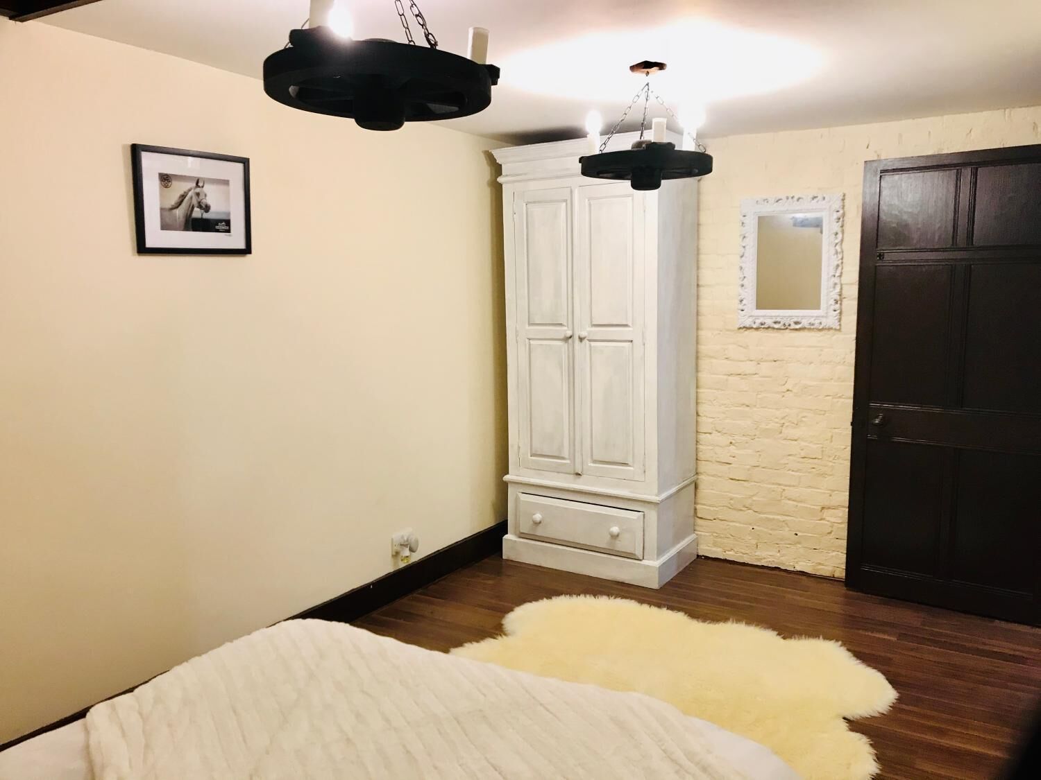 A bedroom with a white wardrobe, a white door, and a framed picture on the wall.