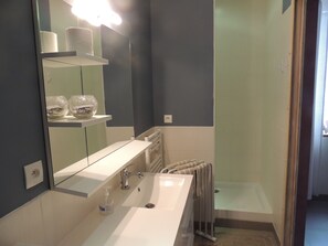 Een moderne badkamer met een wit wastafelmeubel, een grote spiegel en een douchecabine van glas.