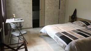Un dormitorio con cama, escritorio y silla. Hay una puerta que da a un armario.