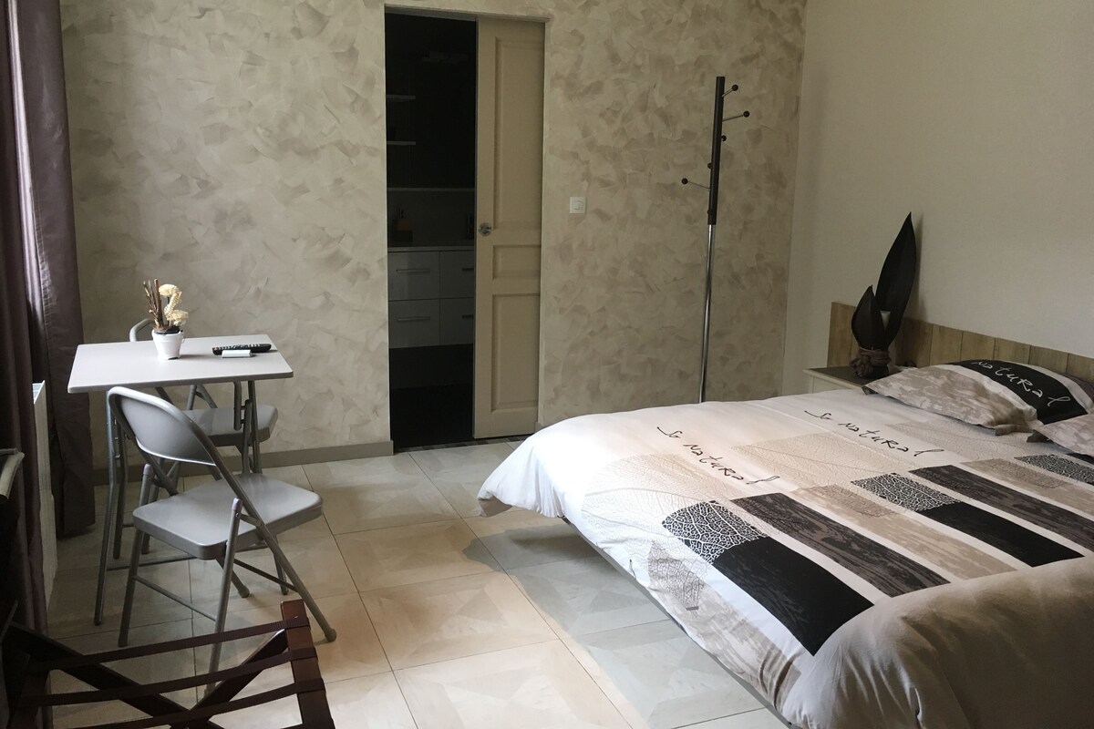 Een slaapkamer met een bed, een bureau en een stoel. Een deur leidt naar een inloopkast.