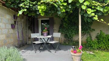 Une terrasse extérieure avec une table et des chaises, entourée de verdure et de plantes en pot.