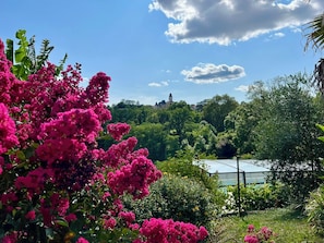 Un jardín con flores rosadas vibrantes y una vista de un edificio con una torre a lo lejos.