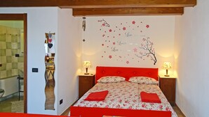 A bedroom with a red bed, floral bedding, two bedside lamps, and a wall decoration with cherry blossoms and inspirational text. - Holideal Casa Paola (Tremosine)