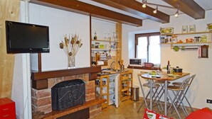 A compact kitchen with a built-in oven, a dining area with a table and chairs, and a TV mounted on the wall. - Holideal Casa Paola (Tremosine)