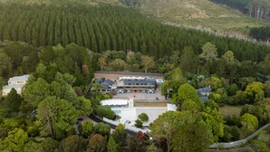 An aerial view of a large, multi-story building surrounded by dense forest.