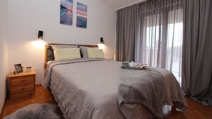 A bedroom with a large bed, wooden nightstand, and a small rug. - Apartments Villa Nikola (Rovinj)
