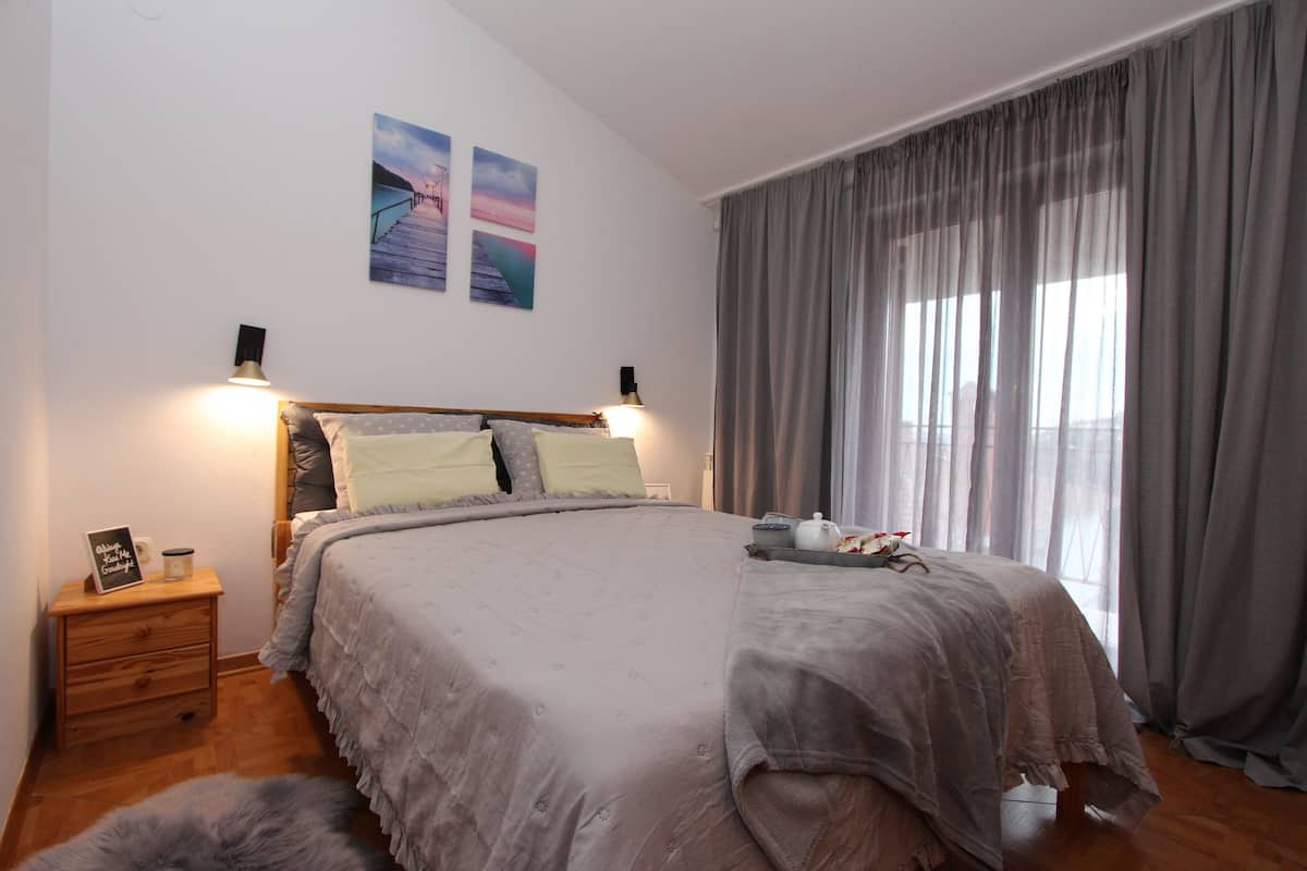 Une chambre avec un grand lit, une table de chevet en bois et un petit tapis.
