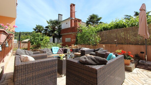 A patio area with wicker furniture, a brick chimney, and potted plants. - Apartments Villa Nikola (Rovinj)