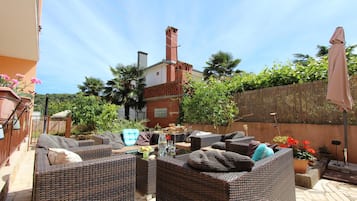 Un patio con mobiliario de mimbre, una chimenea de ladrillo y plantas en macetas.
