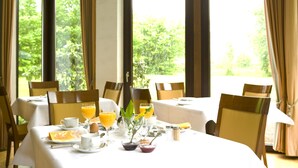 Een ontbijtsetting met een tafel gedekt voor twee personen, inclusief borden, bekers en sapglazen.