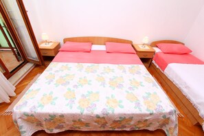 A bedroom with a large bed, two bedside tables with lamps, and a wooden floor. - Apartments Antolovic (Rovinj)