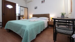 Ein Schlafzimmer mit Bett, Nachttischen, einem Sessel, einem kleinen Tisch und einem Fenster mit Vorhängen.