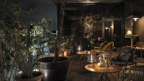 A rooftop terrace with wooden flooring, potted plants, outdoor seating, and ambient lighting. - lyf East Frankfurt (Frankfurt)