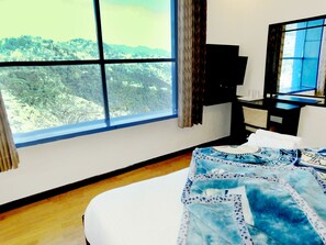 A hotel room with a large window, a bed, a desk, and a television. - Hotel Crystal Palace (Dehradun)