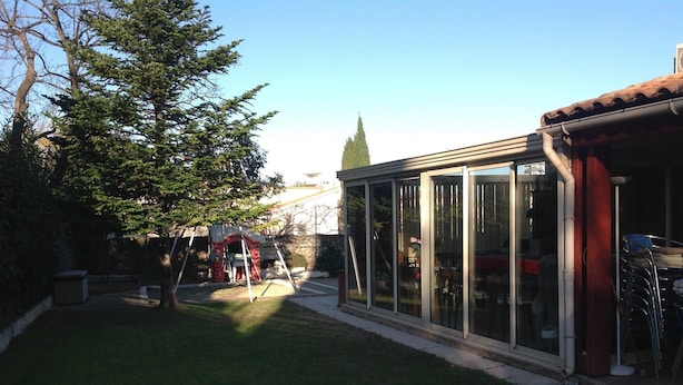 A backyard with a patio area, a swing set, and a covered play structure. - Chambre d'hôtes Fabilio (Marseille)