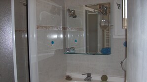 A bathroom with a glass shelf above a sink, a mirror, and a shower area. - Chambre d'hôtes Fabilio (Marseille)