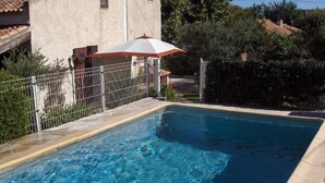 A swimming pool with a metal fence, a lounge chair, and a tiled roof structure. - Chambre d'hôtes Fabilio (Marseille)