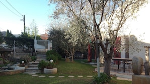 A garden with a stone bench, a small fountain, and a pathway leading to a gate. - Chambre d'hôtes Fabilio (Marseille)
