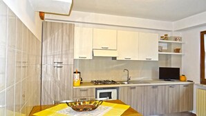 A modern kitchen with a gas stove, sink, and a dining area with a table set for two. - Holideal Casa Rosalia (Tremosine)