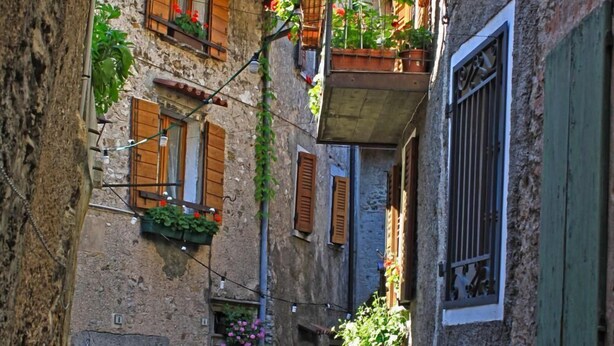 A narrow street with stone buildings, wooden shutters, and flower boxes. - Holideal Casa Rosalia (Tremosine)