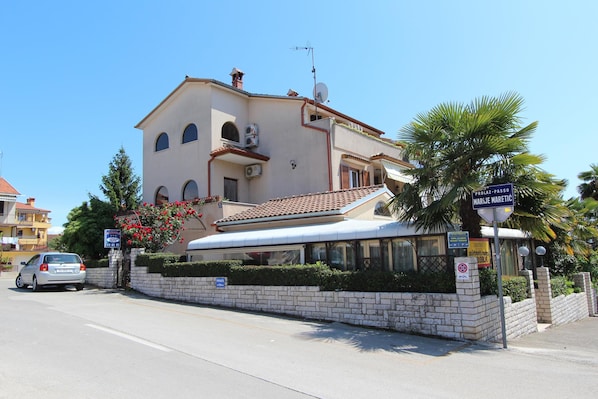 A two-story building with a tiled roof, a balcony, and a sign indicating a parking area.
