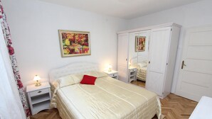 Un dormitorio con cama, mesitas de noche, un armario y un cuadro en la pared.