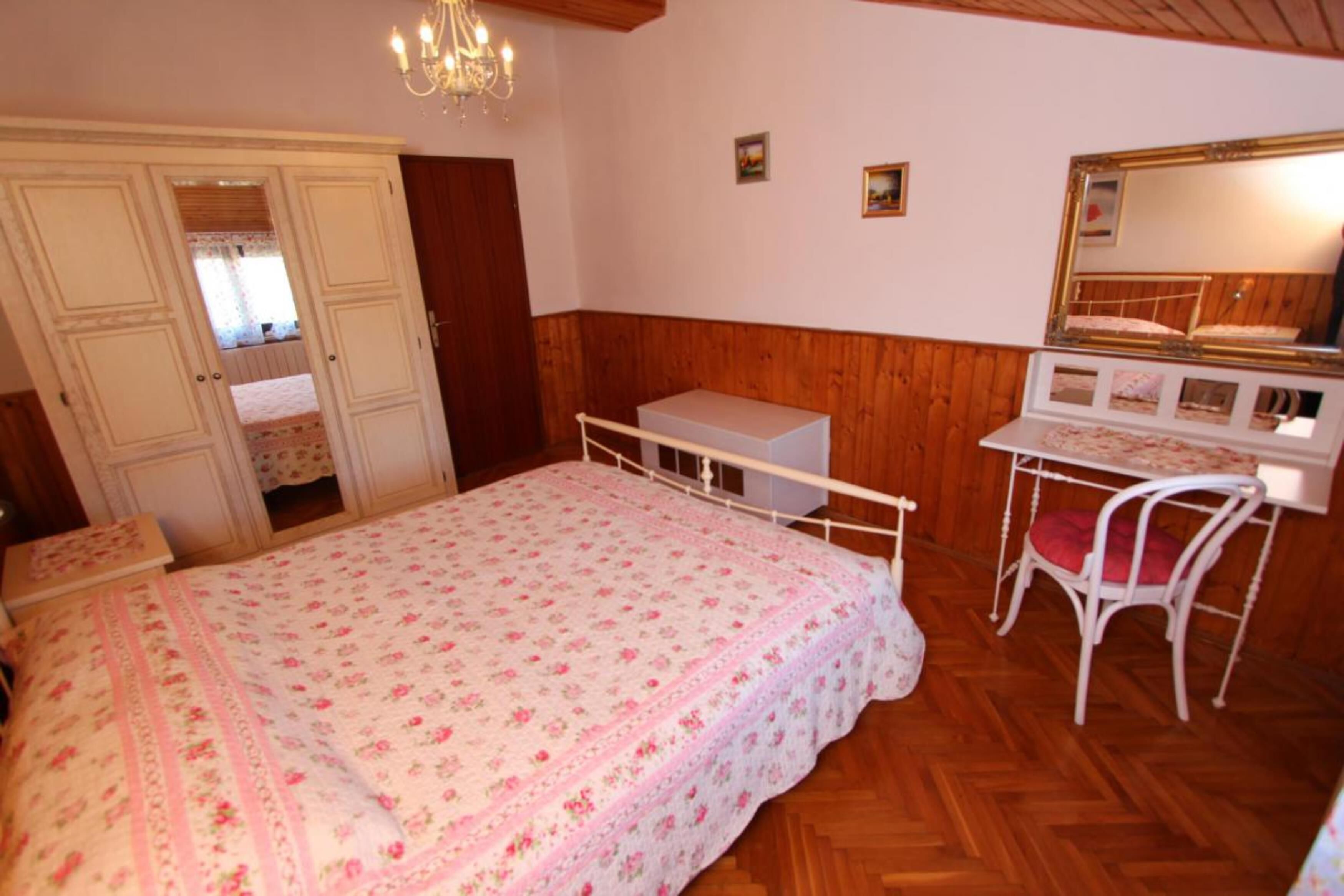 Un dormitorio con cama, escritorio, silla, cómoda y espejo.