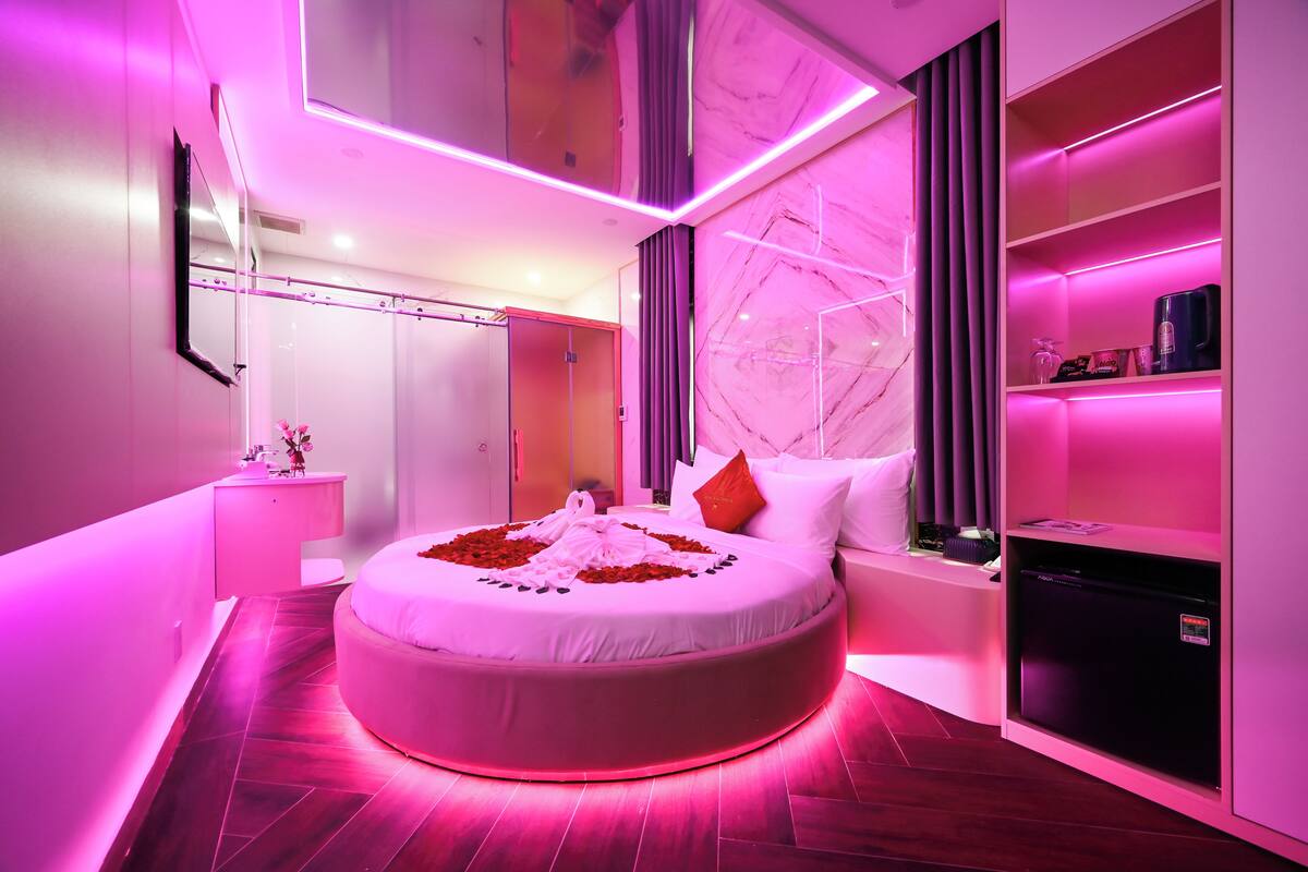 A modern bedroom with a round bed, a vanity, a built-in wardrobe, and a marble wall.