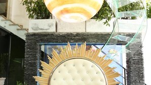 Una sillón lujoso con respaldo capitonado y patas ornamentadas, situado sobre una piscina con fondo de cristal.