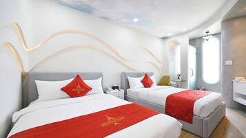 A hotel room with two beds, each with a red bedspread and white pillows. There is a small table with a lamp and a phone. The room has a modern design with a curved ceiling and a window with a view of the sky.