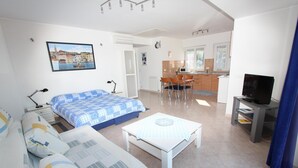 A modern, well-lit room with a bed, sofa, and a dining area with chairs and a table. - Rooms and Apartments Bella Vista (Rovinj)