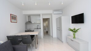 A modern kitchen with white cabinets, a marble countertop, and a flat-screen TV mounted on the wall. - Rooms and Apartments Bella Vista (Rovinj)