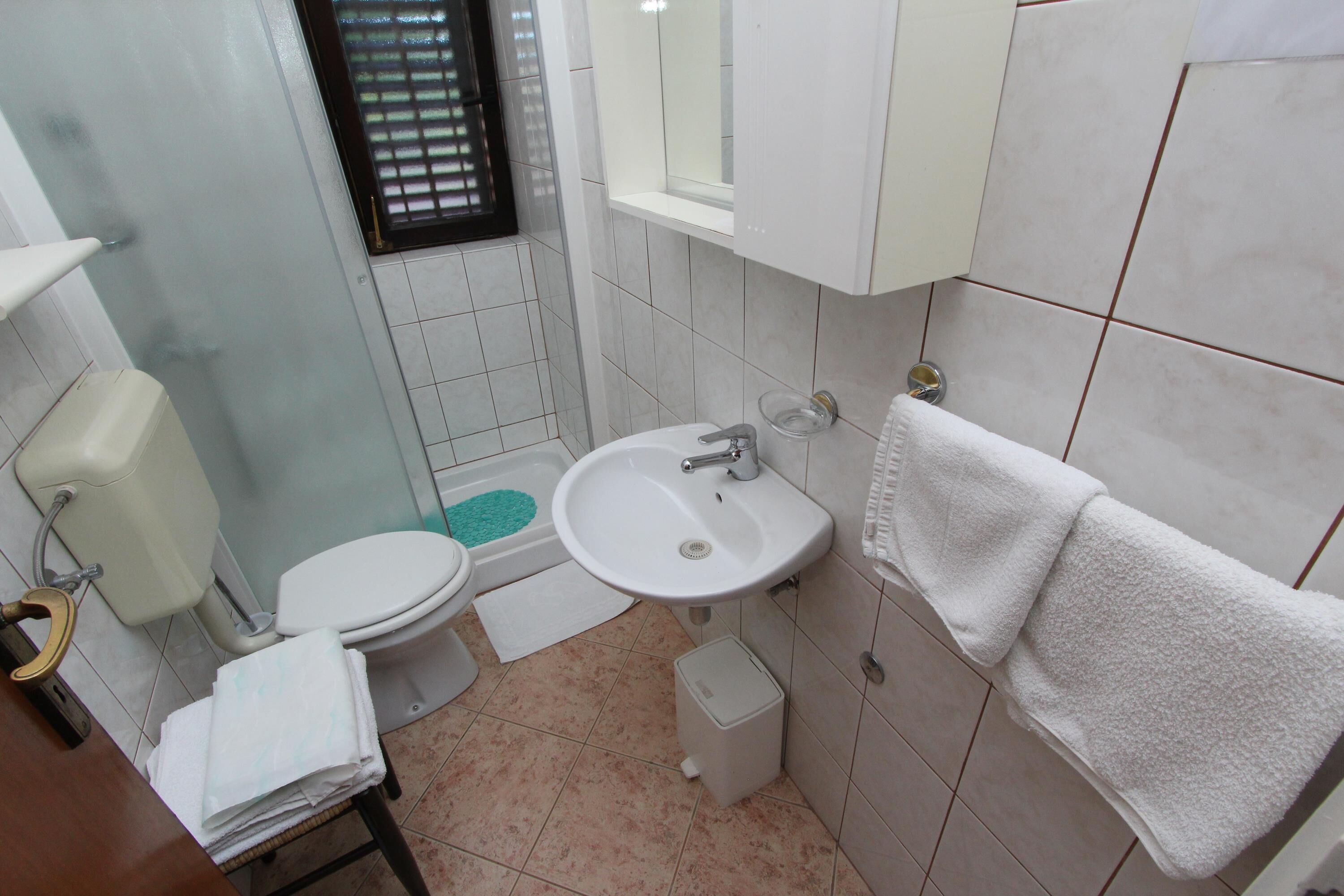 Un baño pequeño con inodoro, lavamanos y una ventana con barrotes.