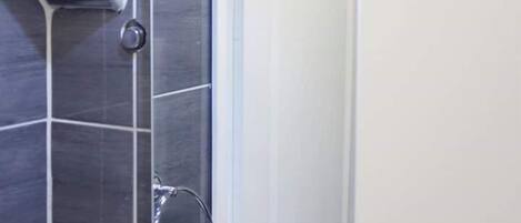 A modern bathroom with a shower, a white sink with toiletries, and a mirror.