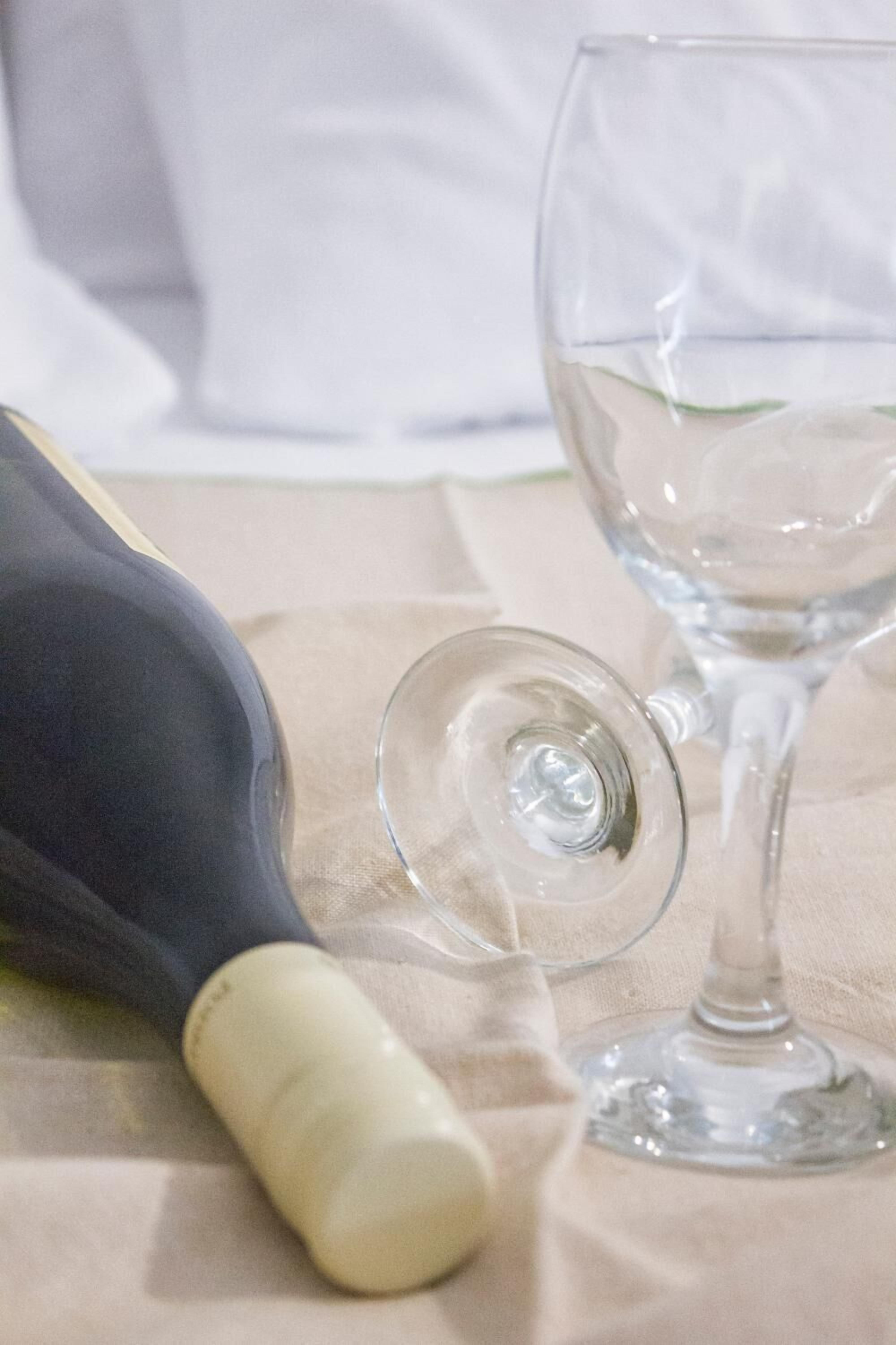 A bottle of white wine and an empty wine glass on a table.
