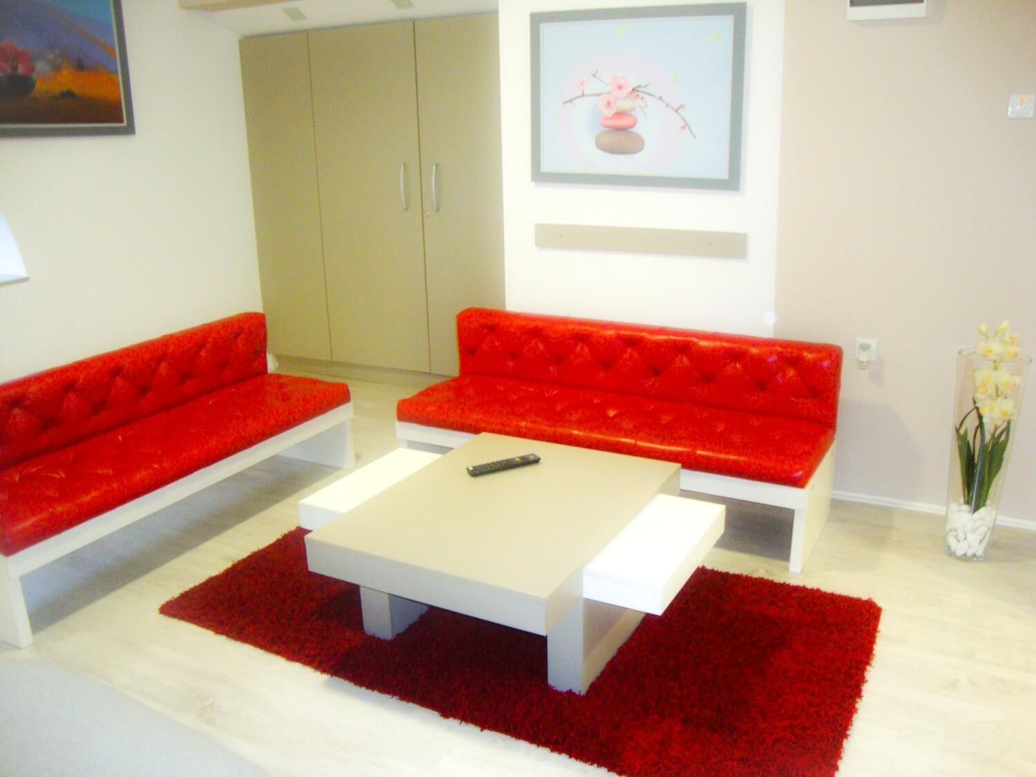 A modern living room with a red sofa set, a white coffee table, and a red rug.