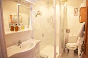 A bathroom with a sink, mirror, shower, and toilet. - Sheephouse Manor (Maidenhead)