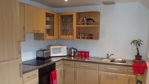 A kitchen with wooden cabinets, a microwave, a toaster, and a sink. - An Cala Cafe and Bunkhouse - Hostel (Lochinver)