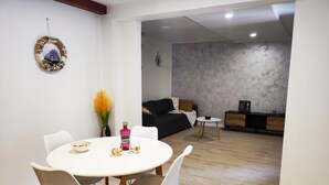 A dining area with a round table and four chairs, a bottle of liquor, and a vase with flowers. - Apartments with Shared Pool Bertetic (Kanfanar)