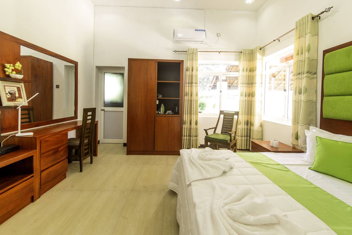 A hotel room with a bed, a desk, a wardrobe, and a chair.