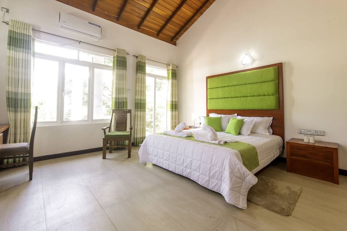 A bedroom with a bed, a chair, a nightstand, and a window with curtains.