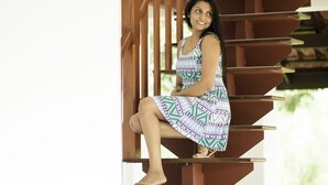 A woman sitting on a wooden staircase with a patterned dress. - Cogent Holiday Home (Udunuwara)