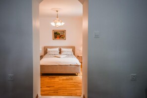 A bedroom with a bed, a chandelier, and a painting on the wall.